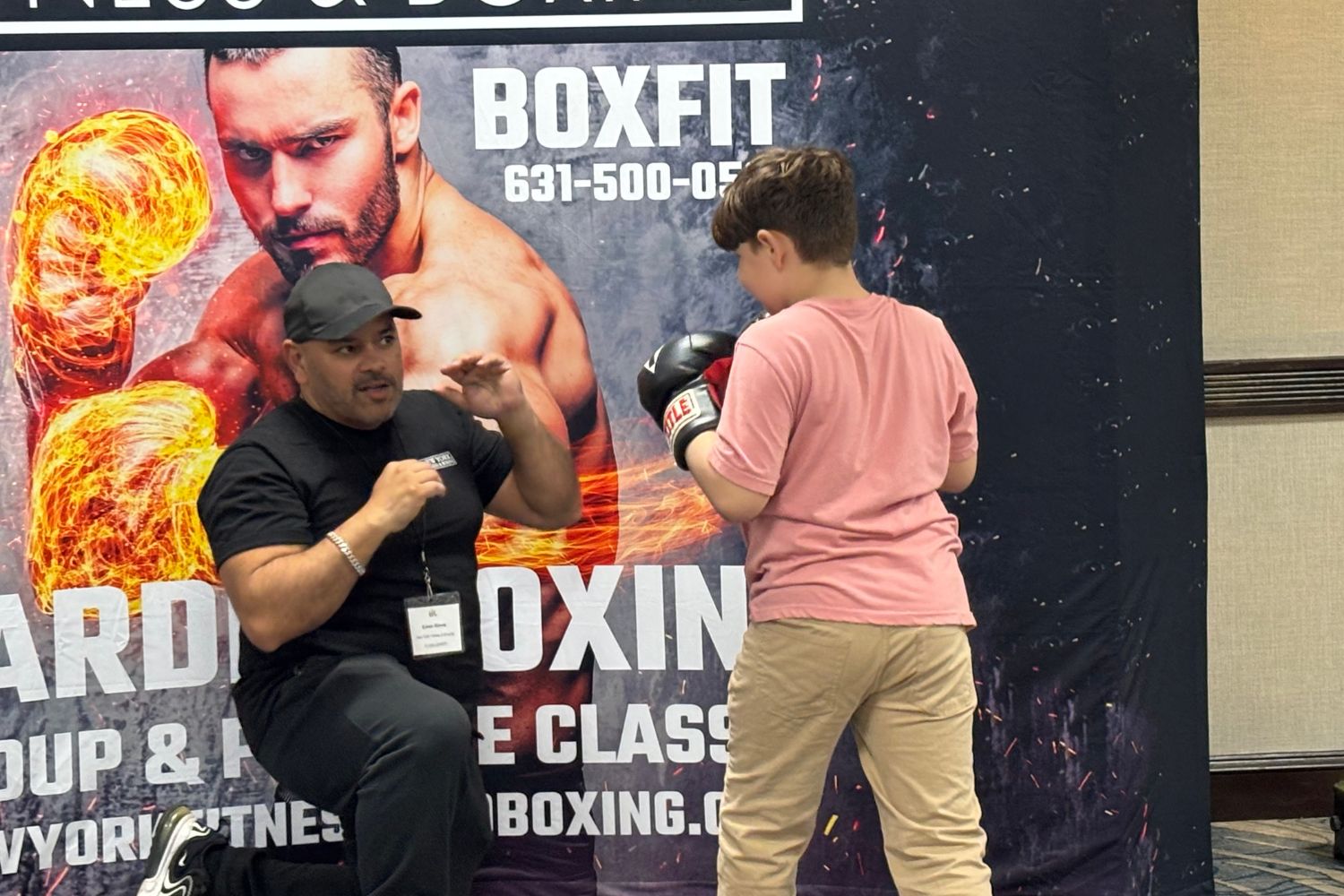 A boy and an instructor spar at a boxing class